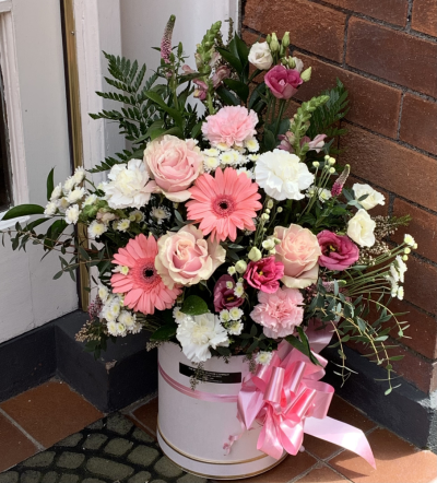 Girlie Pinks Hat Box - A beautiful, vibrant arrangement in a large pink hat box with blooms such as Gerberas, roses, chrysanthemums,carnations and other outstanding stems.