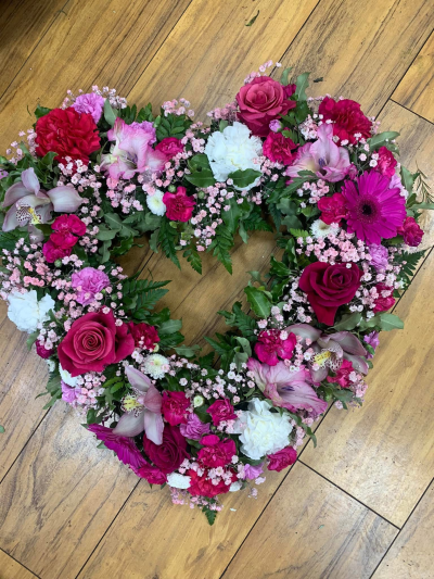 Open pink heart tribute - Gorgeous open heart funeral tribute with lots of seasonal pink blooms.